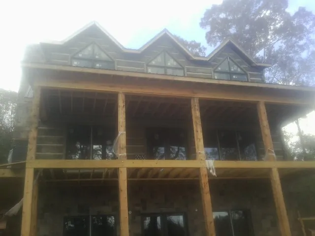 Dormers and porch framing on a large log home under construction — Roof Coating work by our crew in Worton