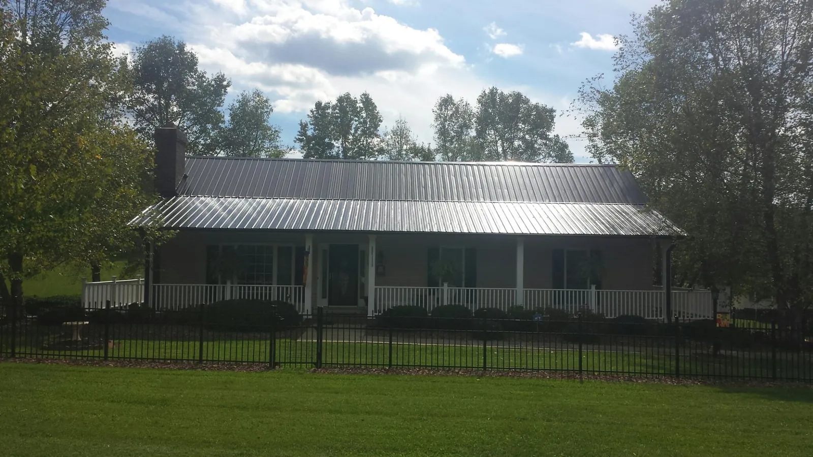 Gray metal roof on a brick ranch with a full width front porch — Gutter Guard Installation work by our crew in Worton