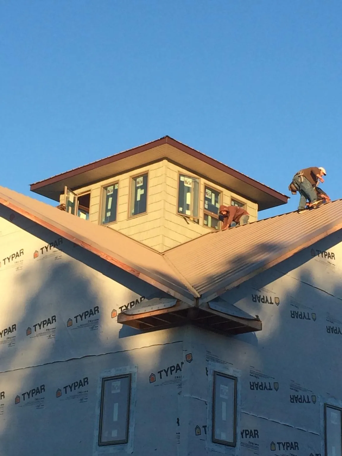 Roofers working around a rooftop cupola on a new metal roof at sunset — Roof Waterproofing in Worton by Roofing Brothers